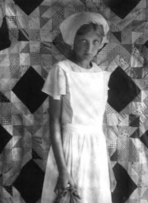 Girl with cap, in front of quilt