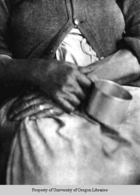 Hands of elderly African-American woman, holding tin cup