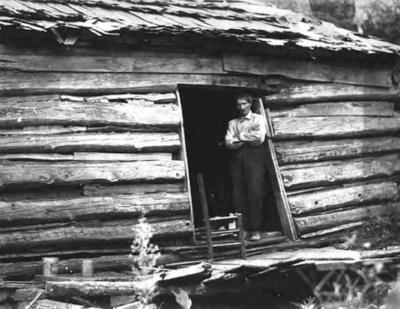 Man in doorway of crude cabin