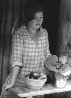 Girl, by bowl of fruit and potted plant